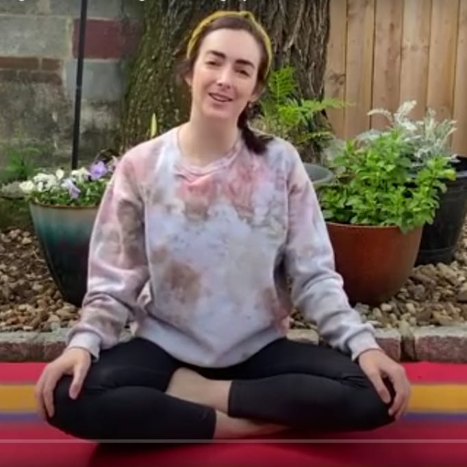 Langley sits in her garden, about to do yoga.