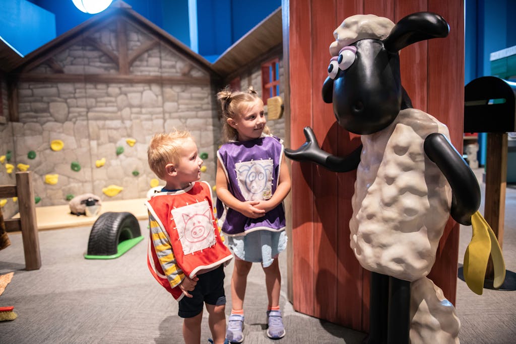 Young boy and girl smiling next to Shaun the Sheep