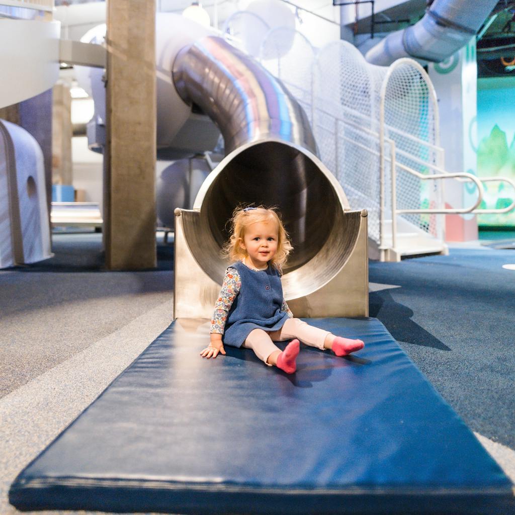 Little girl sliding down the toddler slide in the Dream Machine exhibit
