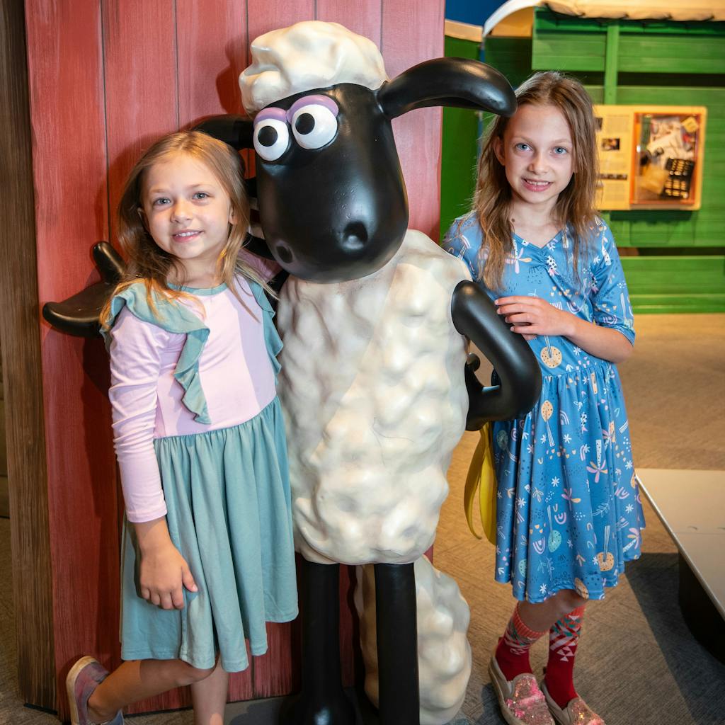 Two girls posing next to Shaun the Sheep