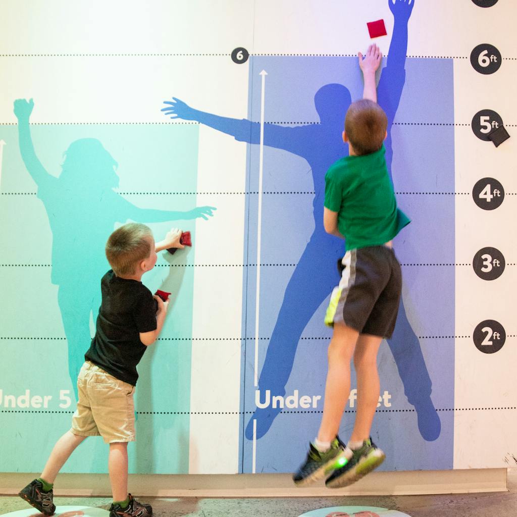 Two boys at the new heights jump wall experience in the Data Science Alley exhibit